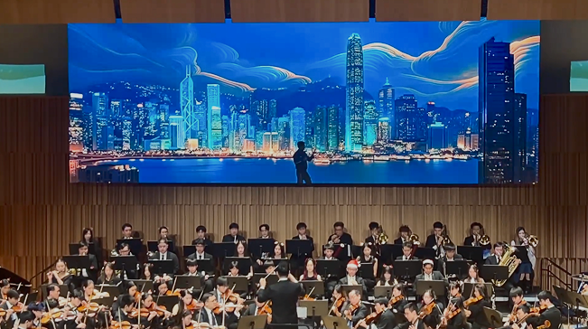 维港 AIGC 画面在音乐会大屏同步播放,前方为乐团与指挥